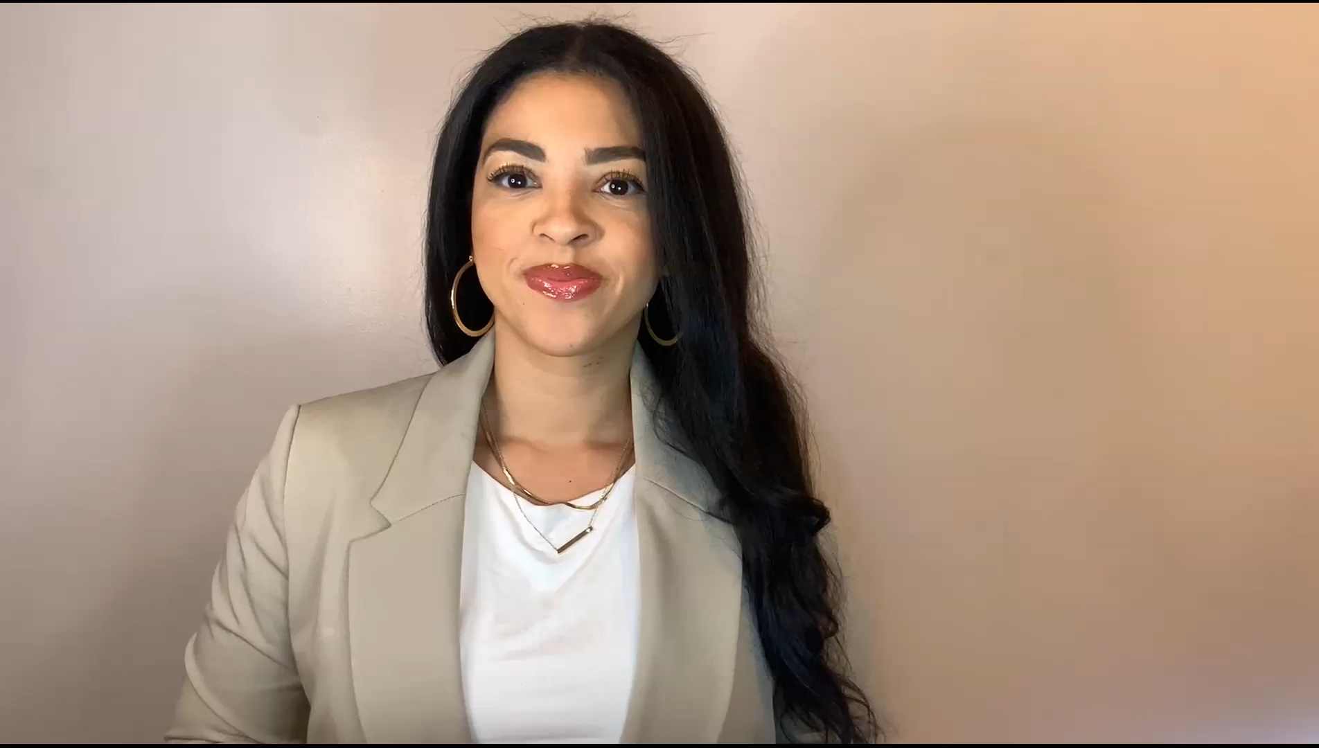 Woman with black hair in brown coat and white shirt.